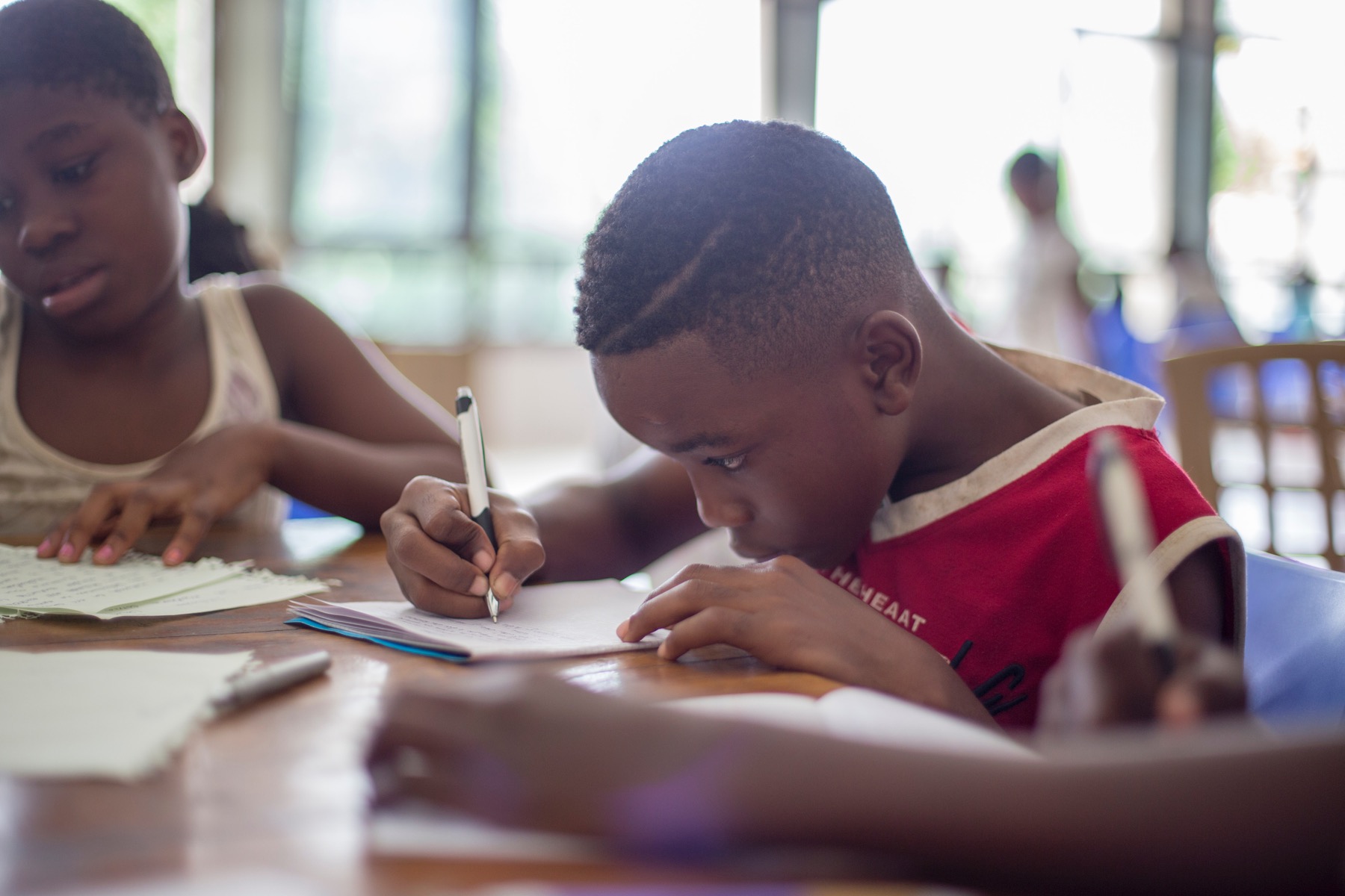 A young student writing intently at a classroom table